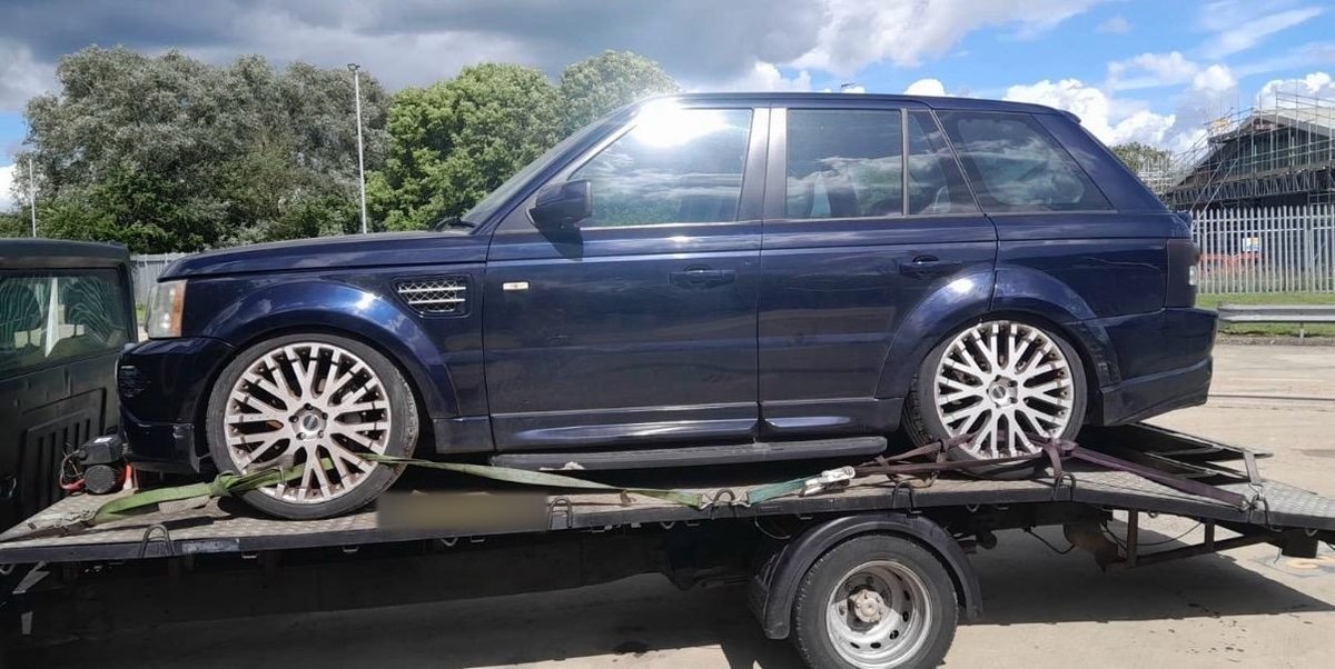 Dark blue Range Rover SUV secured on a flatbed recovery truck